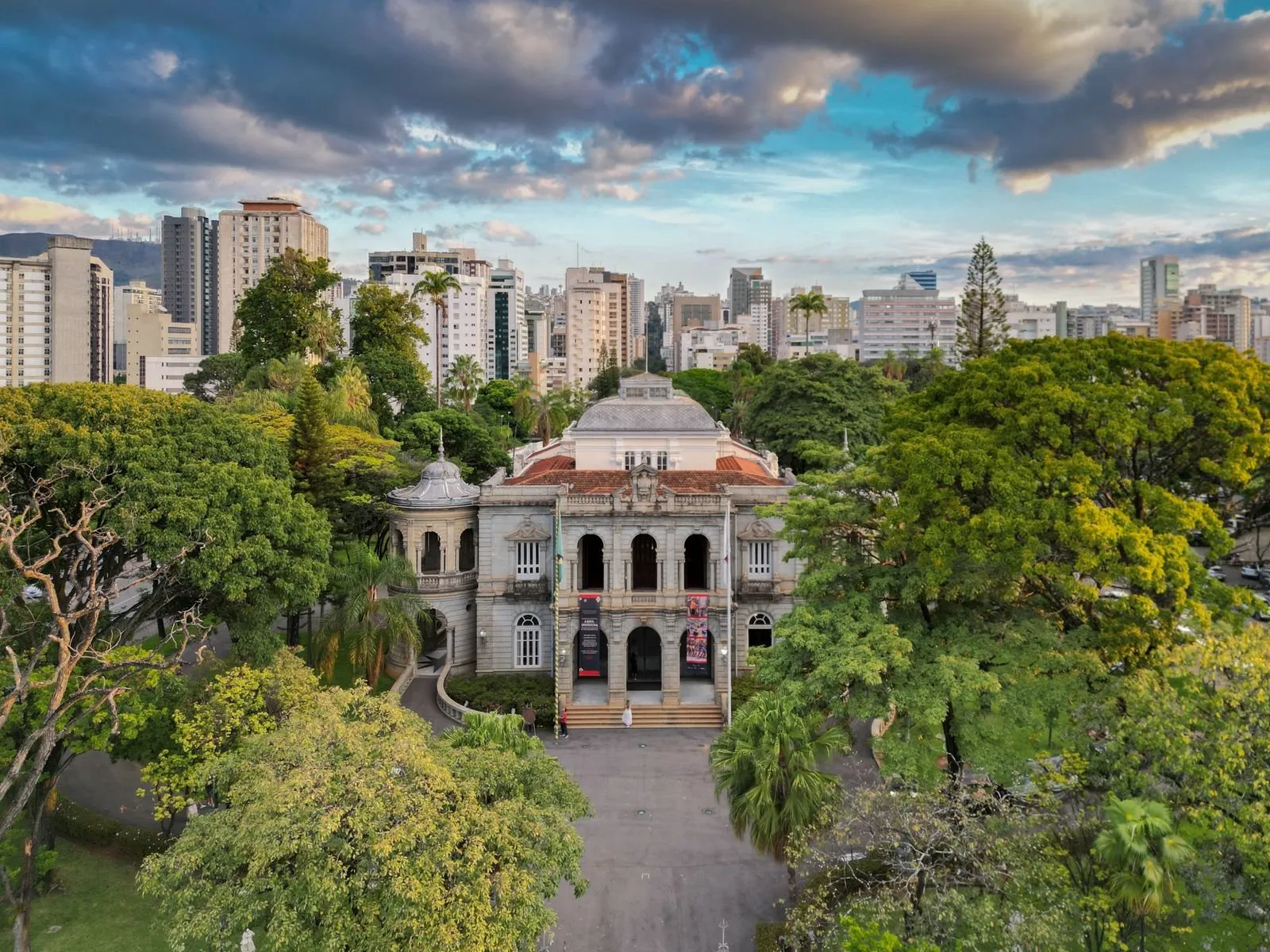Vista aérea do Palácio da Liberdade, em Belo Horizonte, entre árvores, com os prédios da cidade ao fundo